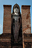 Thailand, Old Sukhothai - Wat Mahathat, 12-metre-tall statue of standing Buddha enshrined in a mandapa on the side of the main chedi. The Buddha is in the 'calling for rain' position. 